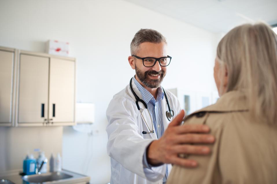 Young doctor greetings elderly patient.