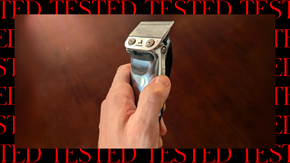 Andis ReVite held in front of a brown surface with a red and black border