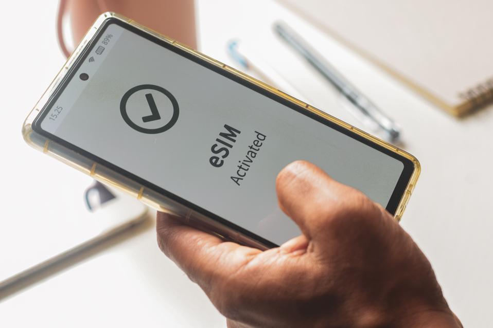 Advantage of embedded SIM connection for network services concept. A person's mobile phone displaying the message eSIM activated successfully.
