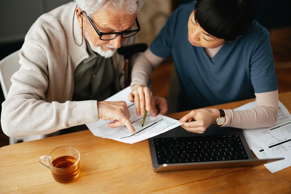 From the above photograph of the elderly men using a computer gear and paying bills with a serious sister