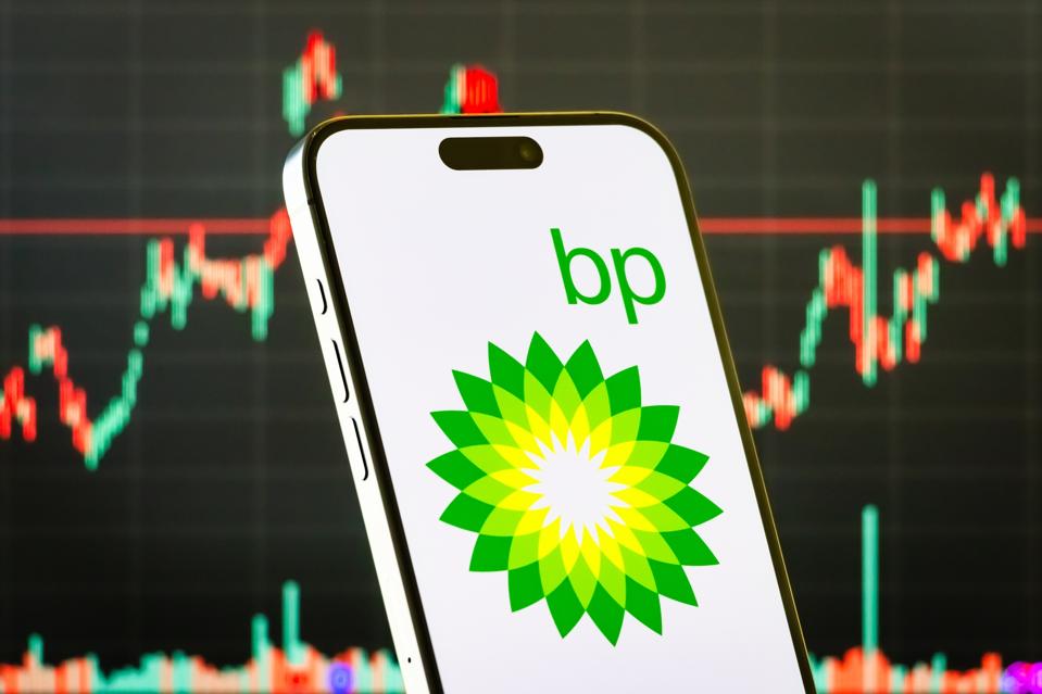 BP plc logo on smartphone with stock market chart background