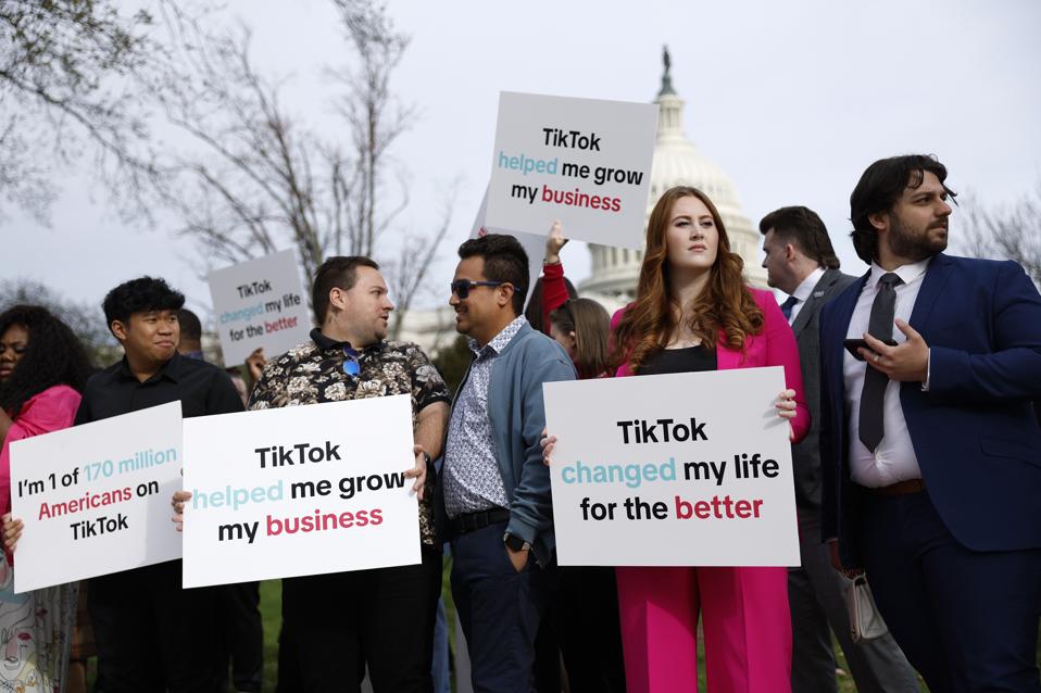 Opponents hold signs protesting a potential TikTok ban