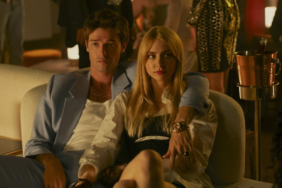 A man sitting on a couch with his left arm around a woman.