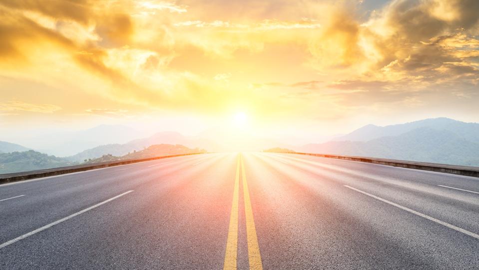 asphalt road and mountains with foggy landscape at sunset
