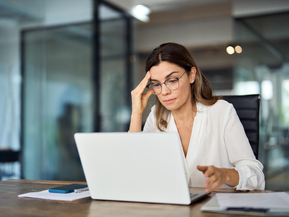 Worried fatigued mature business woman wearing glasses having headache at work.