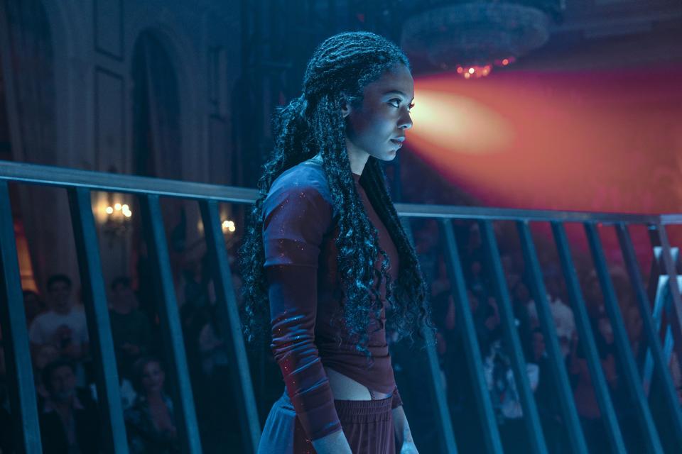 A woman with dark brown braids wearing a red outfit.