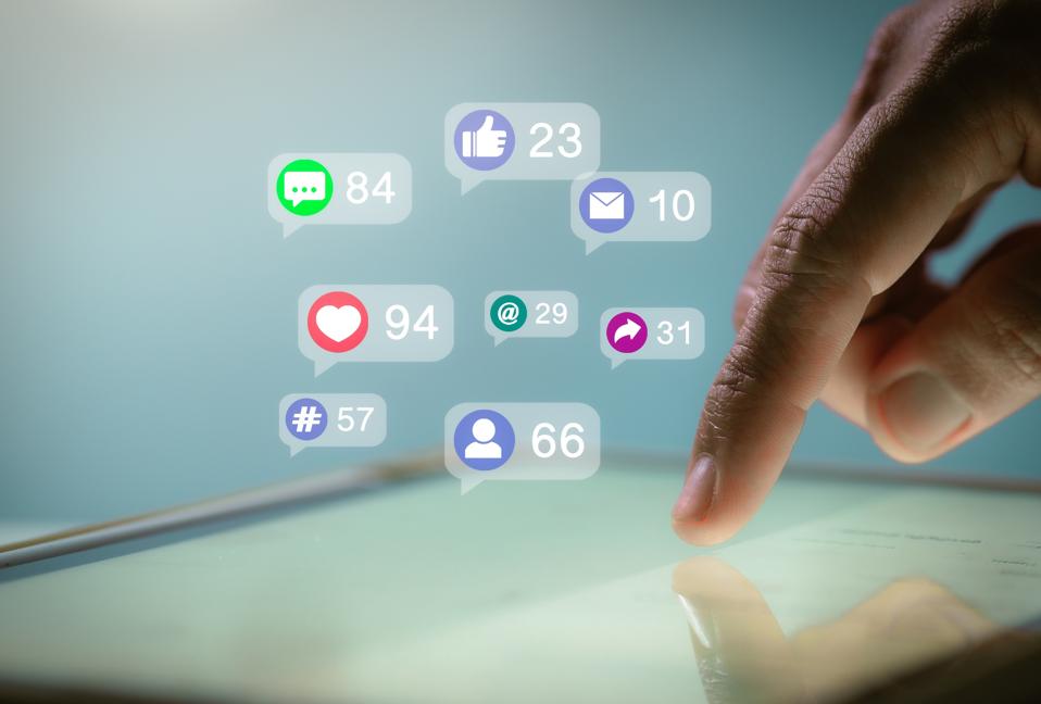 Finger using touchscreen to see social media post's comments, likes, shares and hashtags.