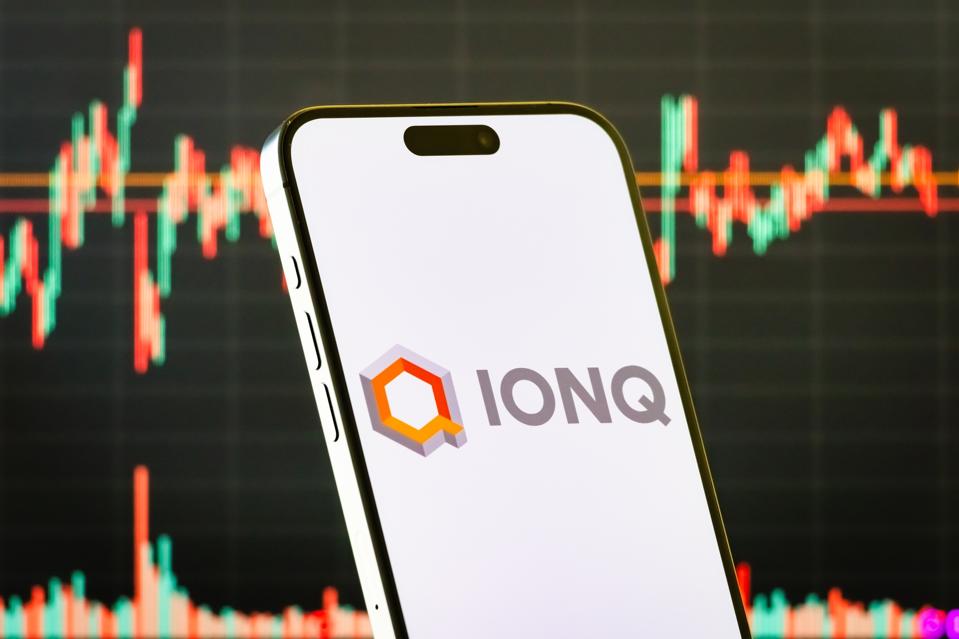 IonQ Inc. logo on smartphone with stock market chart background