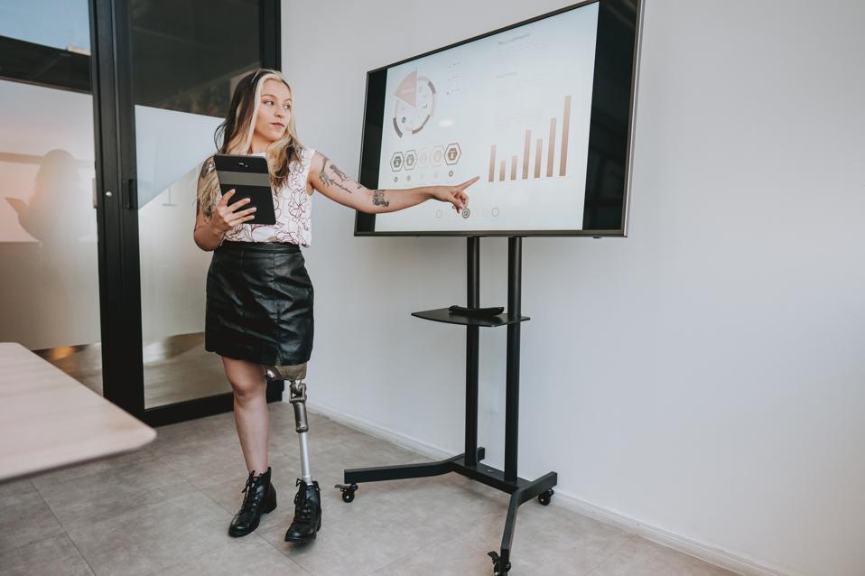 Woman with prosthetic leg presenting financial results 