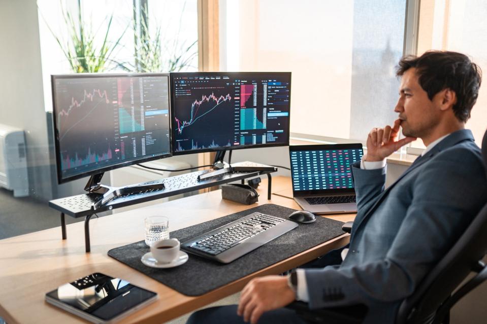 Focused Asian Stock Broker Analyzing Market Data in Modern Office