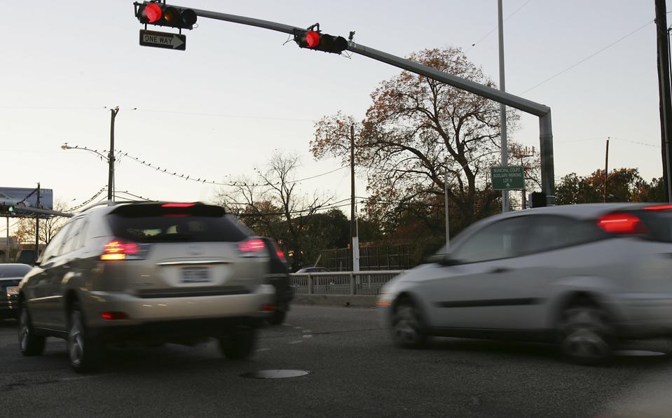 Photo of automobiles running a red light at an intersection.