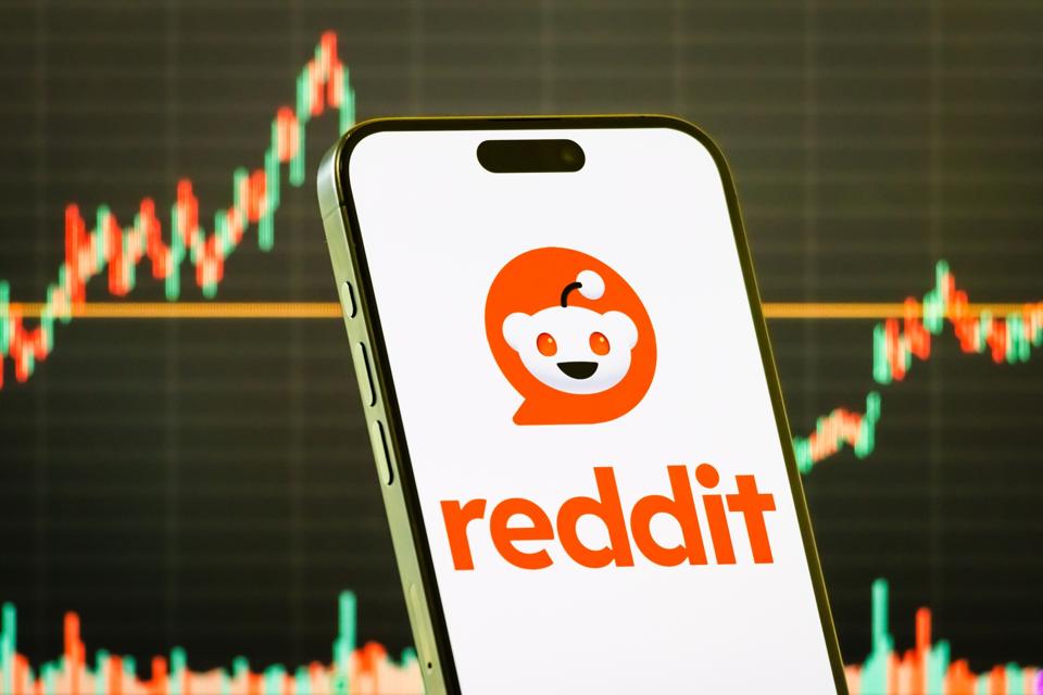 Reddit Inc. logo displayed on smartphone screen with stock market chart in background