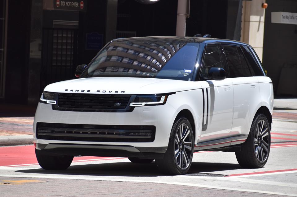 A portrait of a black and white Land Rover Range Rover SUV cruising in a downtown district