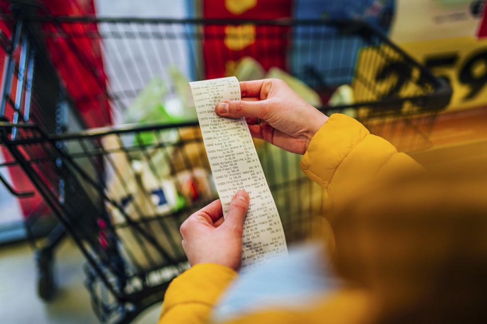 Picture of person checking the bill in front of a shopping cart