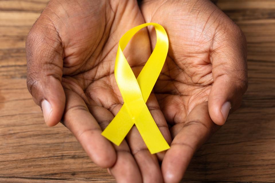 hands holding yellow ribbon for suicide prevention