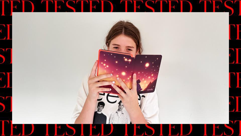 A tween holding the Kindle Colorsoft Kids up to her face against a white wall.