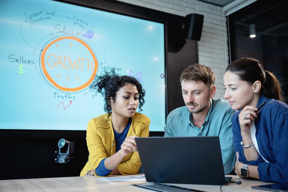 Team-building promotes creativity and enhances problem-solving skills that can drive business growth. Business development team on a strategy meeting while discussing business data insight over a laptop in a modern office.