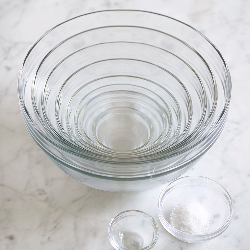 Stack of 10 glass mixing bowls on white marble surface