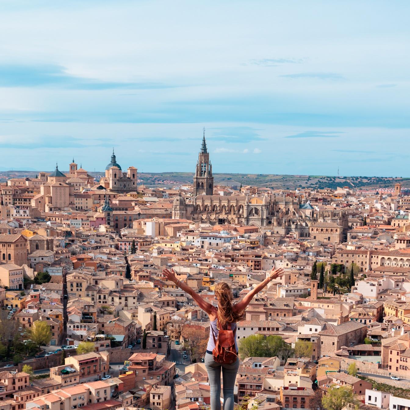 Woman standing on balcony in front of the skyline from Toledo, Spain