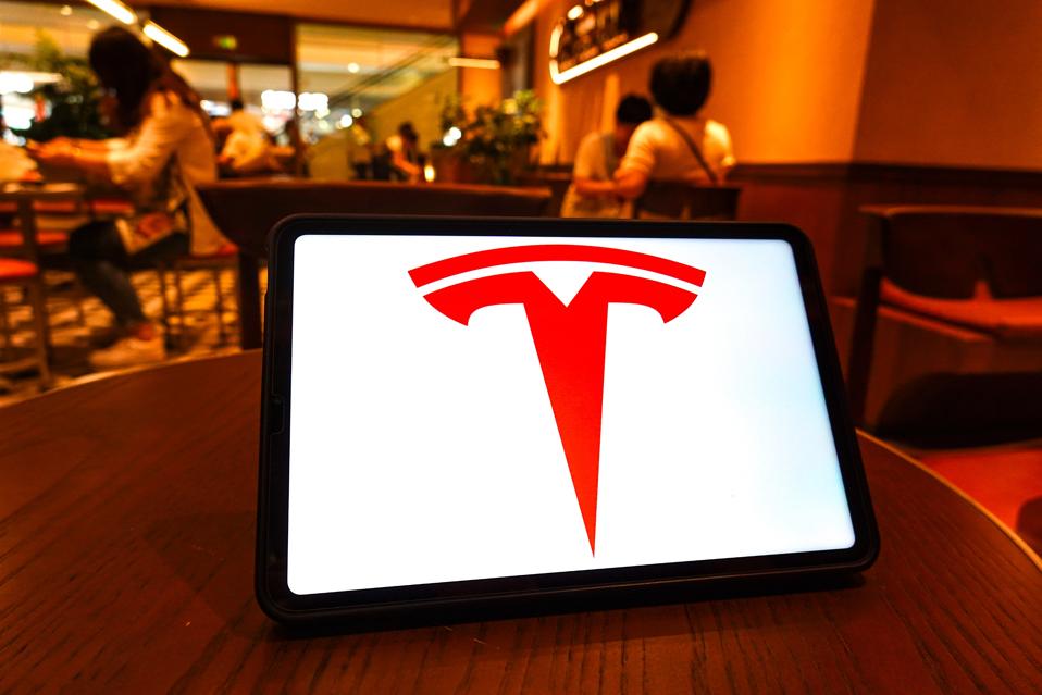 In this photo illustration, the Tesla logo is seen displayed...