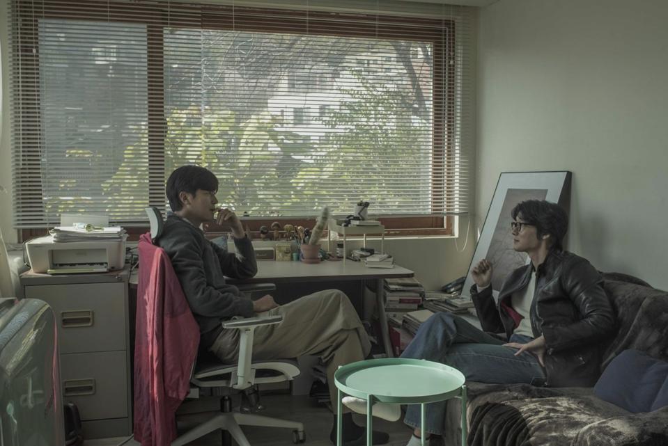 Two men talk in an office.