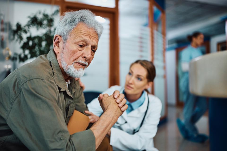 Worried senior man with female doctor in waiting room at the clinic.