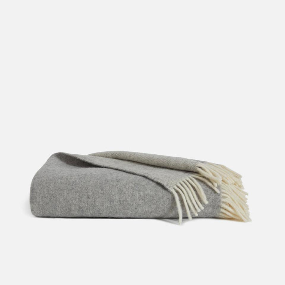The Brooklinen Pure Wool Throw Blanket in color greige folded up against white background