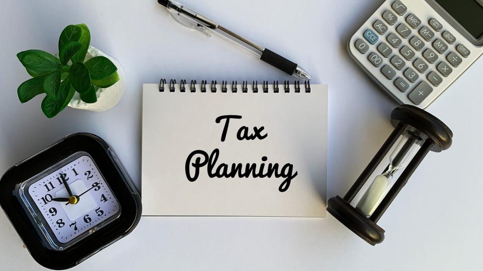 Tax planning text on notepad with calculator, clock and pen background. Business concept.