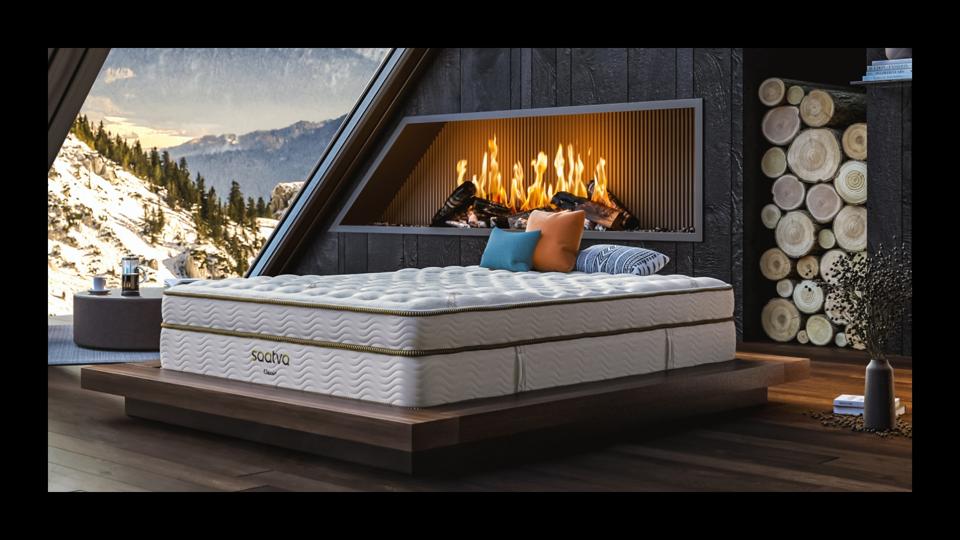 The Saatva Classic Mattress on top of a wooden foundation bed frame. 