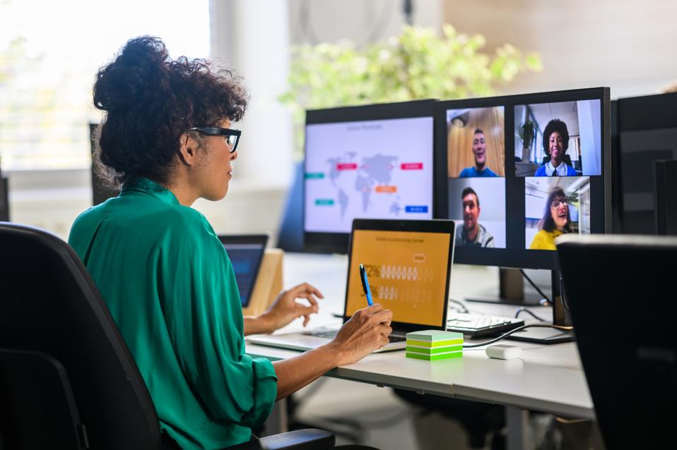 Woman leading a virtual meeting while discussing a report with remote job team members.
