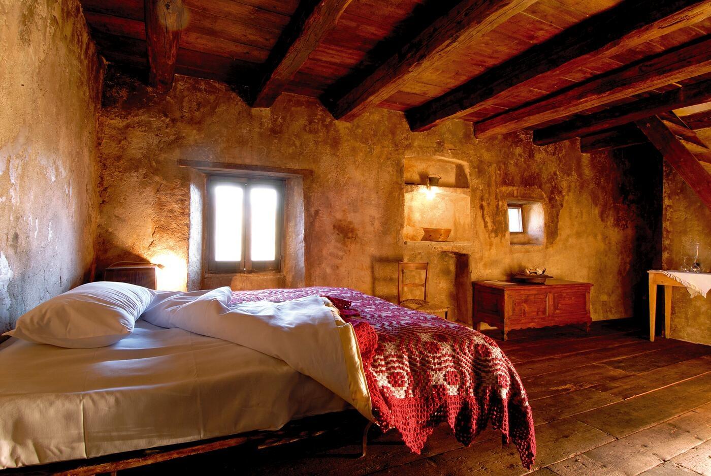 A guest room at Sextantio Santo Stefano hotel in Abruzzo, Italy, has a red bedspread