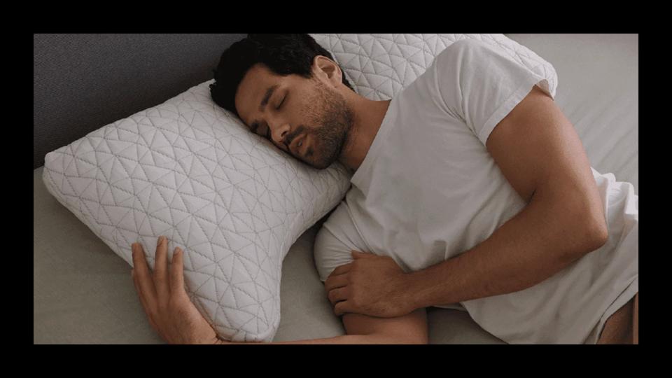 A man lying on his side on the Coop Sleep Adjustable Pillow with a black border