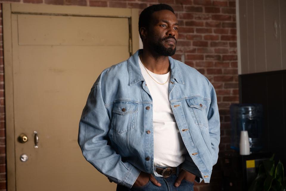 A man wearing a white t-shirt and blue jean jacket