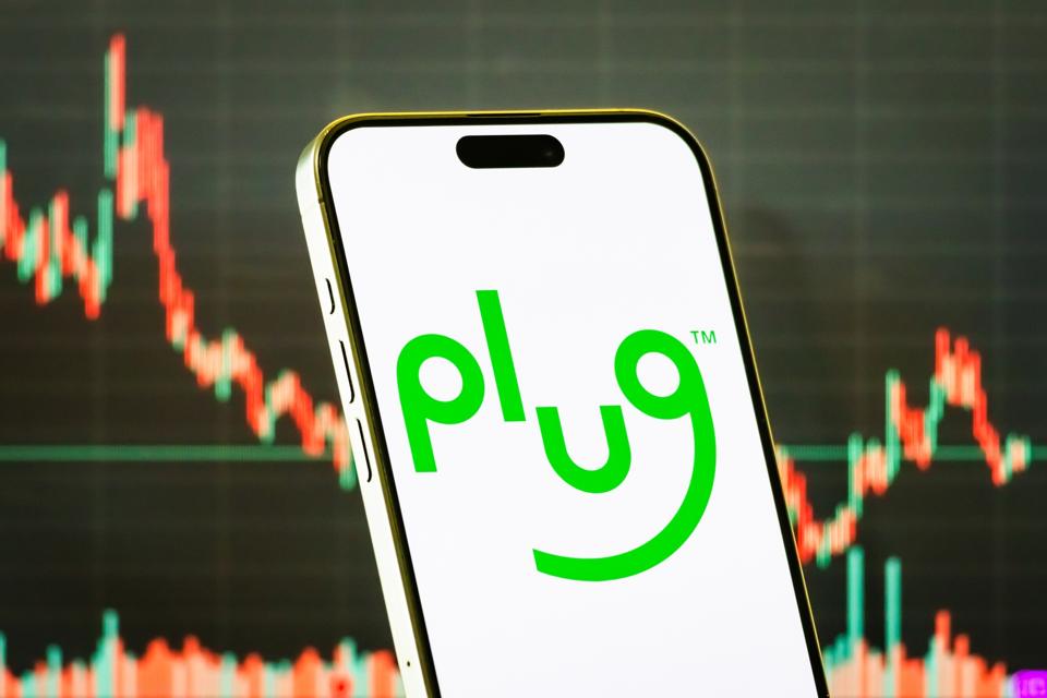 Plug Power Inc. logo on smartphone with stock market chart background
