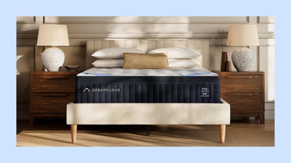 Photo of DreamCloud Premier Hybrid Mattress on a plush, cream bed frame in a modern bedroom.