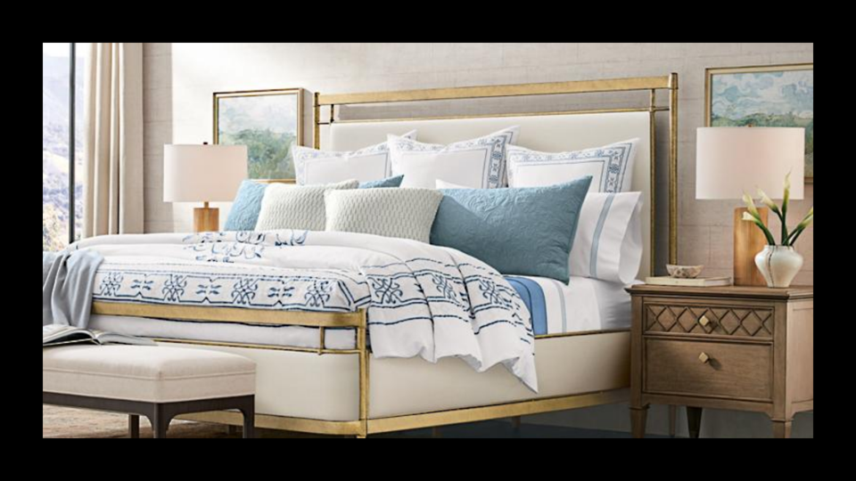 A bed with white and blue bedding and pillows with nightstands and lamps on each side.