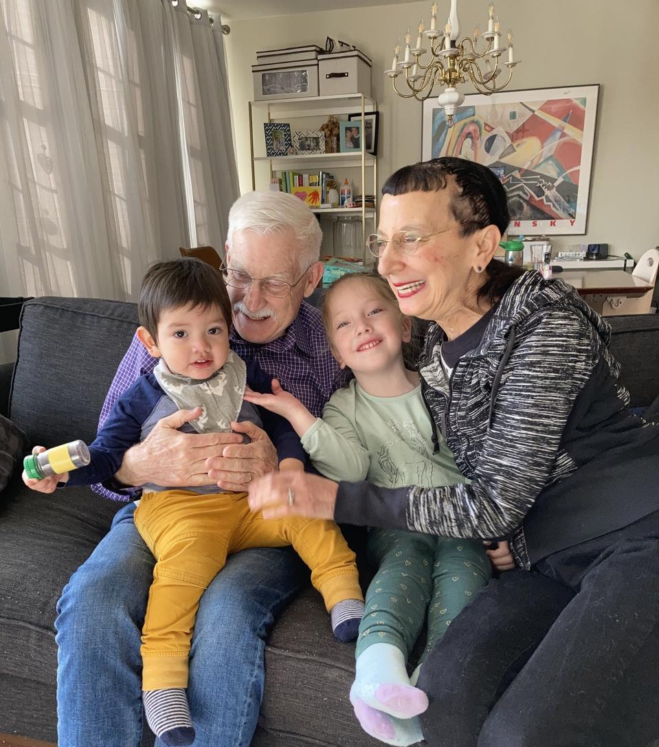 Two small children being held by two seniors on a couch