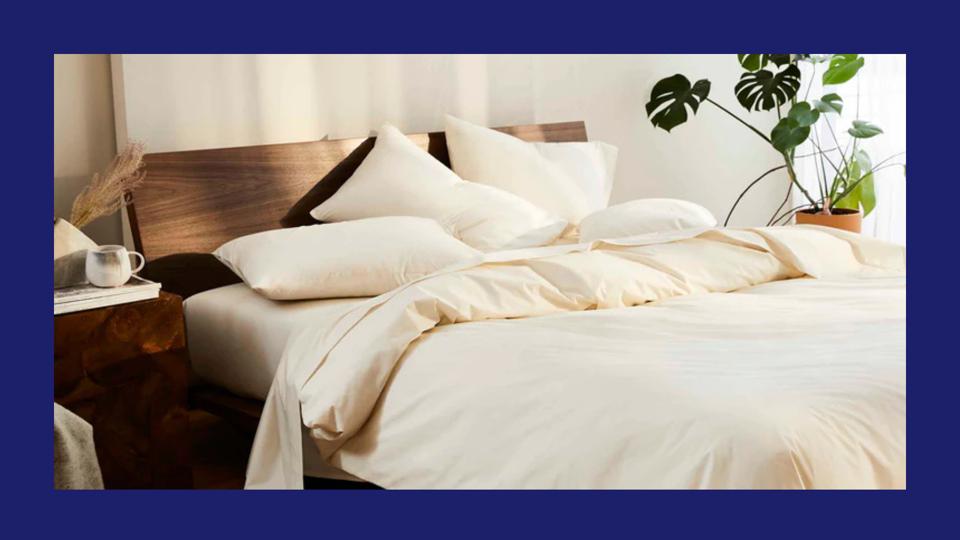 Photo of a cozy bed with cream percale Brooklinen sheets and duvet cover.