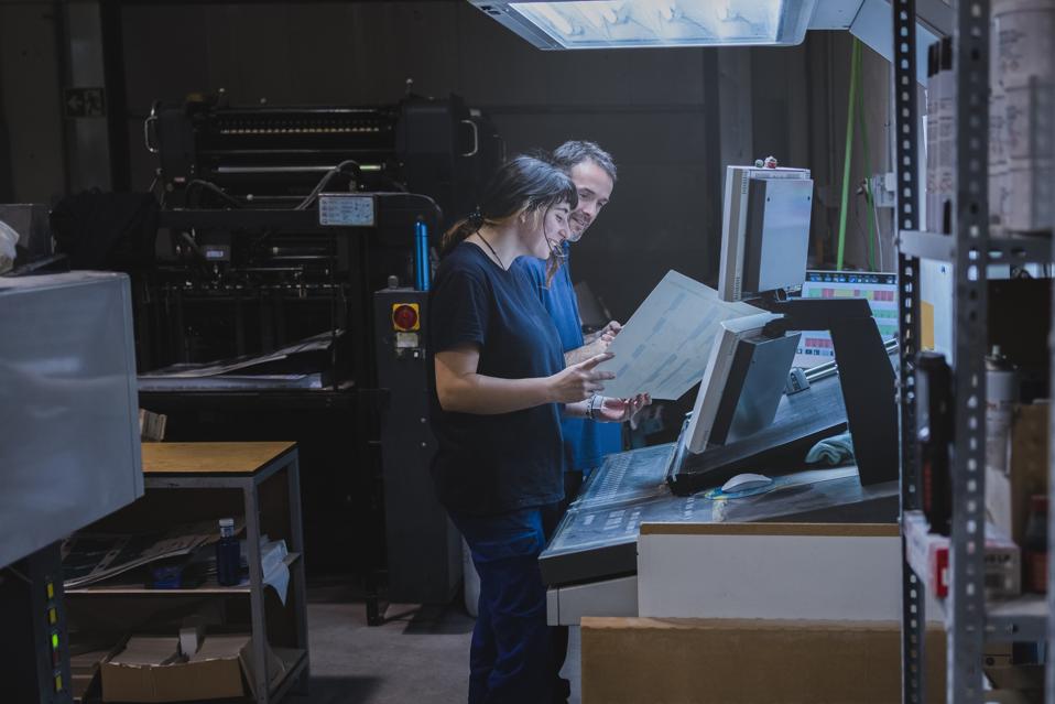 "Duo of male and female workers cooperating in an offset printing factory"