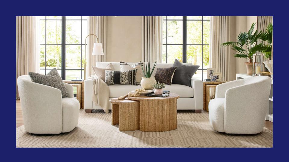 A modern traditional living room with white sofa and two white armchairs on a neutral rug.