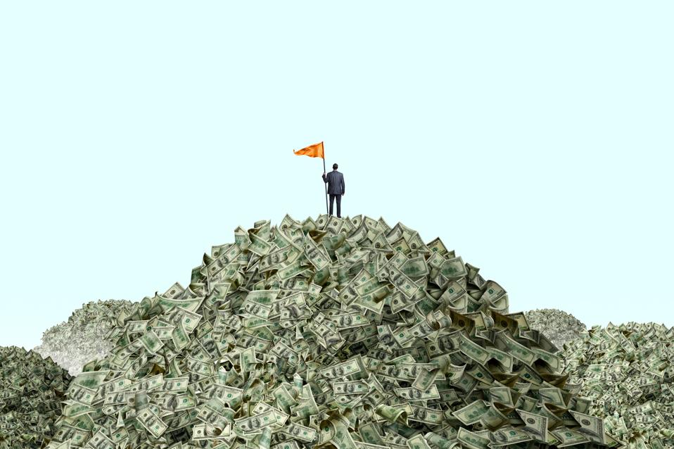 Man planting a flag on piles of cash