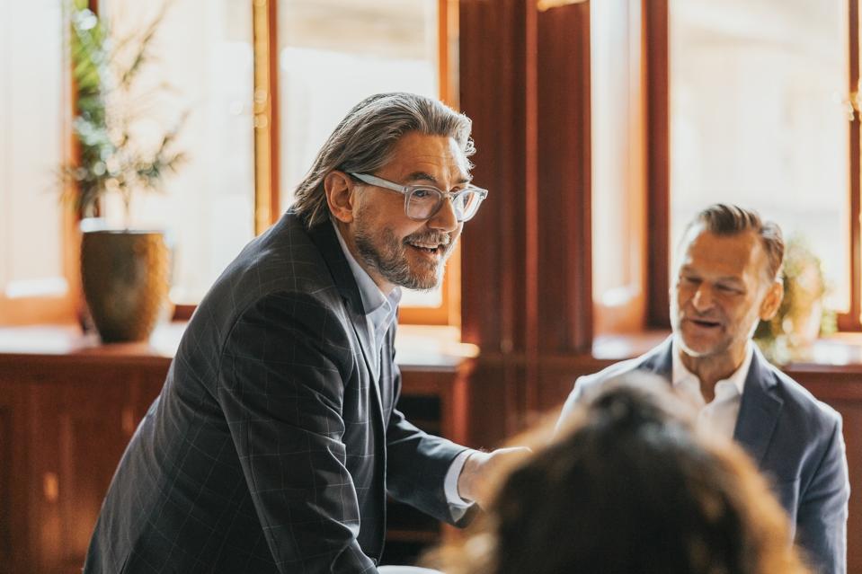 Smiling male manager talking with colleagues in meeting room at office