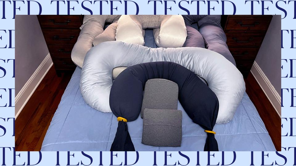 Photo: Pile of pregnancy pillows on a bed. Photo is framed by a pattern that says “Tested”