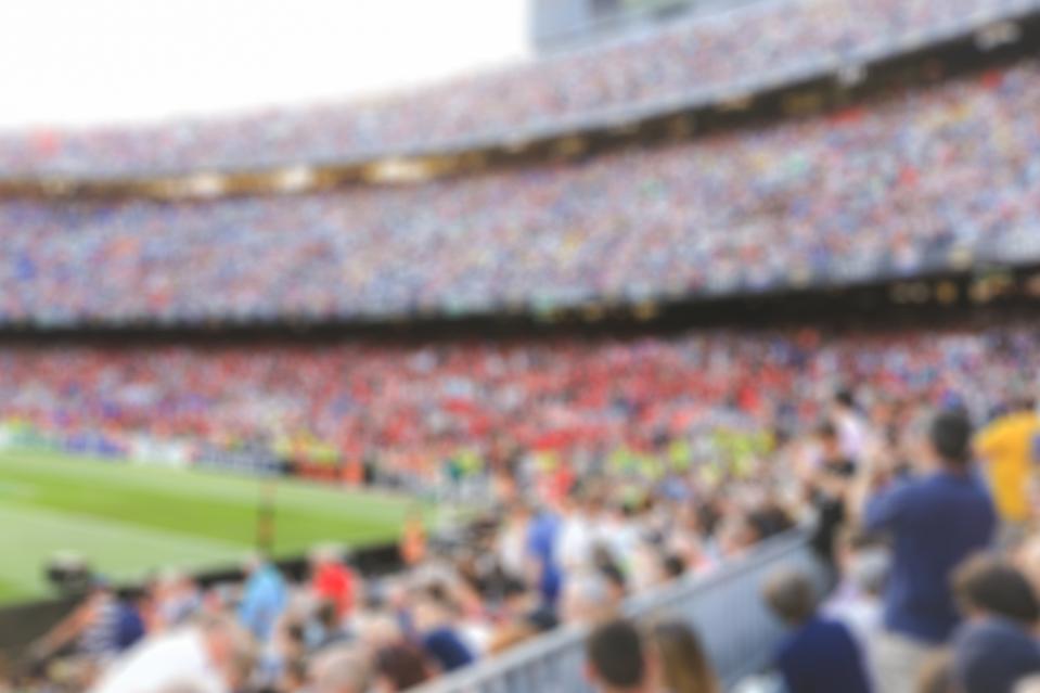 Blurred photo of a crowded sports stadium symbolizing the death of fans and fandom.