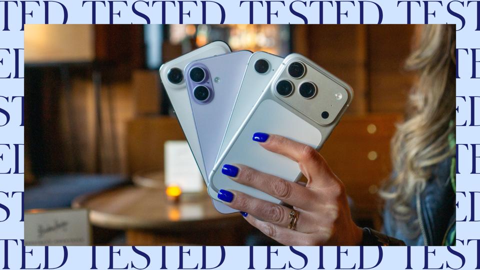 A hand holding four different iPhones.