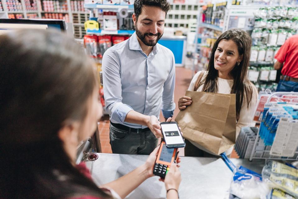 Mature man doing a contactless payment with mobile phone at hardware store