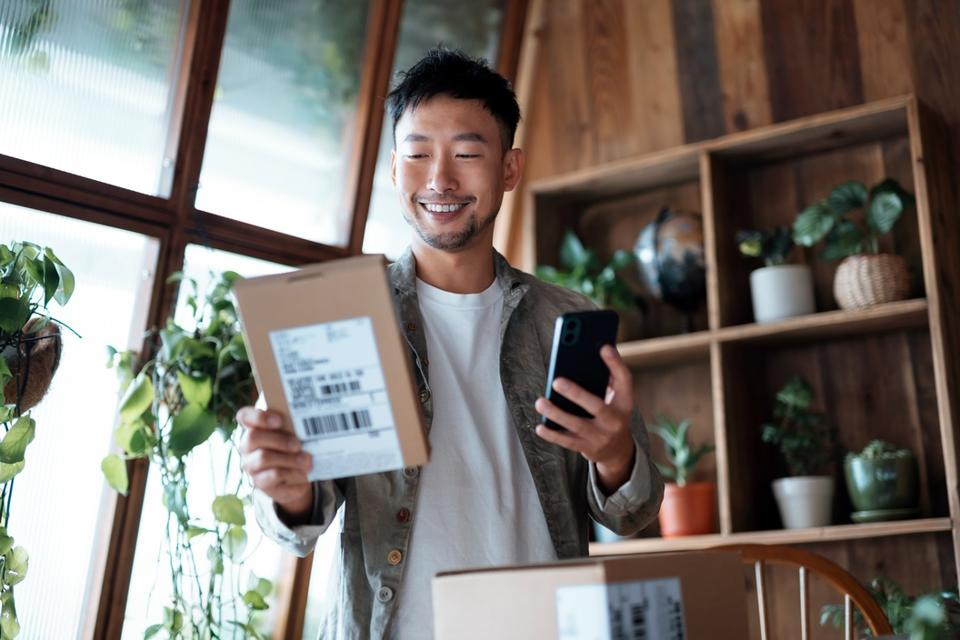 Young man smiling as he holds a package he's just received. 