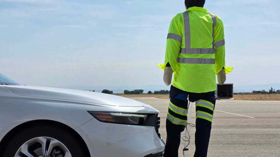 A roadside assistance worker in high-vis gear near a vehicle.