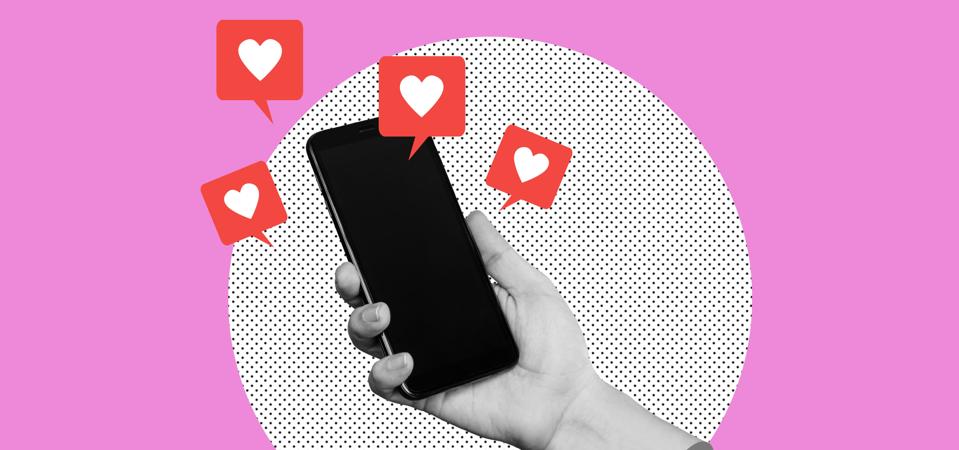 Black blank screen of mobile phone with like symbols from social networks in female hand