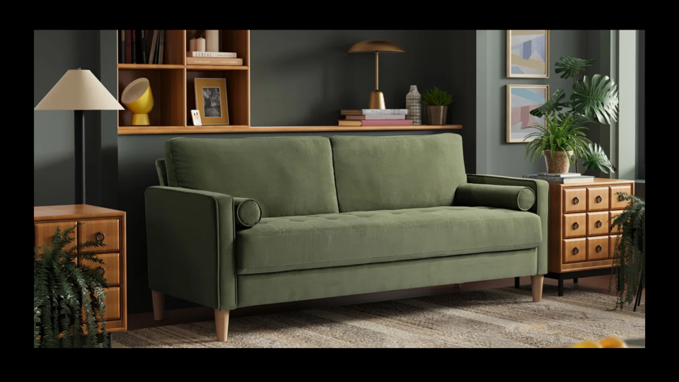 Green Mercury Row sofa with wooden end tables in front of a black wall.